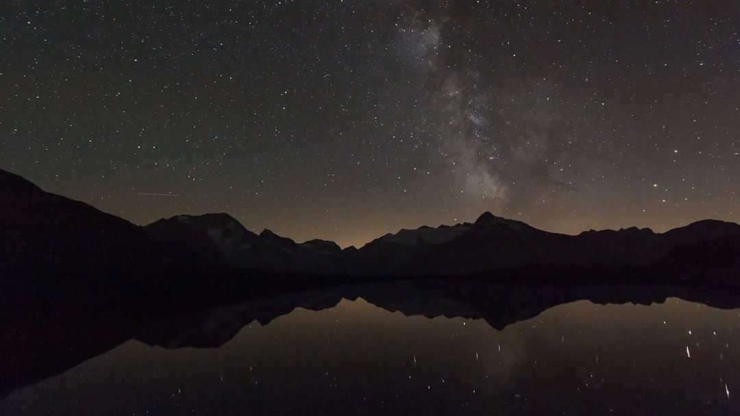A northern mountain lake under a star-filled night sky